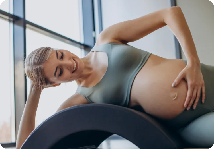 pregnant-woman-exercising-with-help-reformer-pilates-class